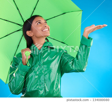 Happy, winter and a woman with an umbrella for the rain isolated on a blue background. Smile, insurance and a girl feeling for drops of water, bad weather and drizzling with shelter on a backdrop Happy, winter and a woman with an umbrella for the rain isolated on a blue background. Smile, insurance and a girl feeling for drops of water, bad weather and drizzling with shelter on a backdrop 134080080