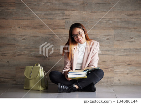 University, portrait of happy woman on floor with books on mockup space and education at college. Information, knowledge and backpack, student sitting on wall background with smile and book to study. University, portrait of happy woman on floor with books on mockup space and education at college. Information, knowledge and backpack, student sitting on wall background with smile and book to study. 134080144