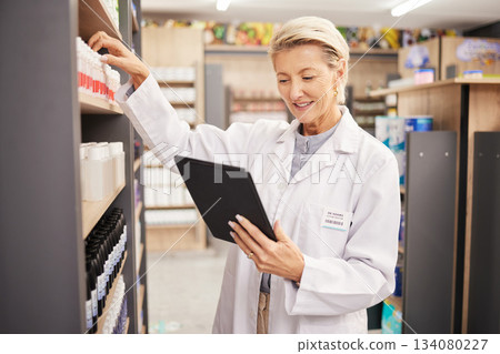 Pharmacist, stock or woman with tablet, check inventory or medication information with technology. Mature female, lady or medical professional with device, pharmacy or supplements with online reading 134080227