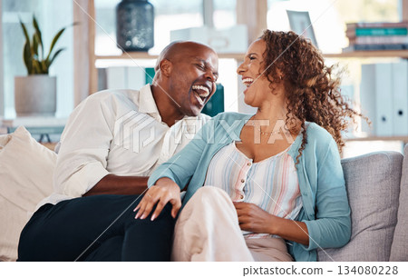 Love, happy and couple laugh on sofa for bonding, quality time and relaxing together at home. Marriage, interracial relationship and man and woman on couch embrace, hugging and laughing at funny joke 134080228