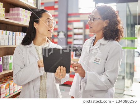 Pharmacy, tablet and stock with women in a dispensary talking about prescription medicine for an online order. Healthcare, technology or diversity with a female pharmacist team working in a drugstore 134080250