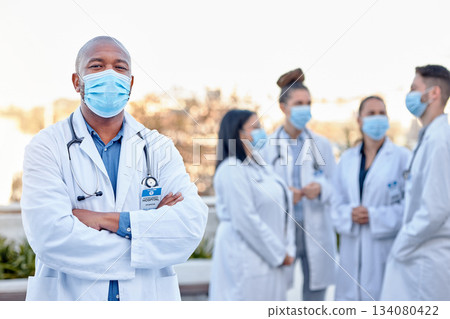 Covid, portrait and proud man doctor outside of hospital with team for planning, teamwork and strategy. Face, healthcare and male leader with doctors for innovation, brainstorm and corona management 134080422