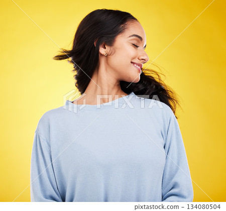 Freedom, shake hair and woman in studio with beauty and smile, satisfaction and gen z, fashion on yellow background. Happiness, youth and Indian female is happy with haircare and cosmetics with shine 134080504