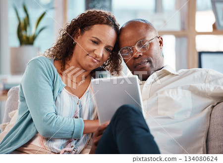 Mature couple, tablet and sofa in home living room for bonding, love and video on app for memory. Black man, woman and mobile touchscreen to watch movie on internet in house on lounge couch to relax 134080624