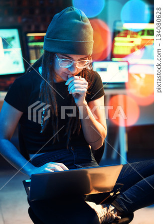 Woman, laptop and hacker thinking, typing or programming, software or cybersecurity. Neon, computer and it coder or programmer reading information for hacking idea while on dark web at night in home. Woman, laptop and hacker thinking, typing or programming, software or cybersecurity. Neon, computer and it coder or programmer reading information for hacking idea while on dark web at night in home. 134080628