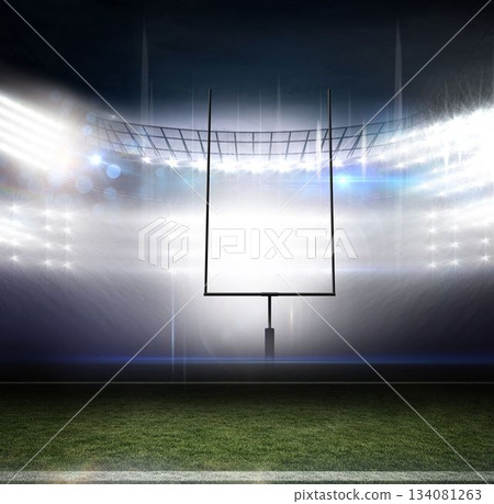 Empty football turf glowing under floodlights in stadium, goalpost rising with yard line marker 134081263