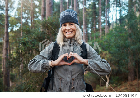 Portrait, heart and happy woman in forest hiking, fitness and health support, self care hands and cardiovascular workout. Nature, travel or trekking of mature person in woods with love sign or emoji 134081407