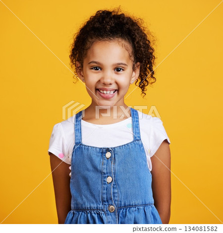 Studio, portrait and happy child with a smile on face isolated on a yellow background. Cute hispanic young girl kid model with happiness, carefree and positive attitude in casual clothes for fashion 134081582