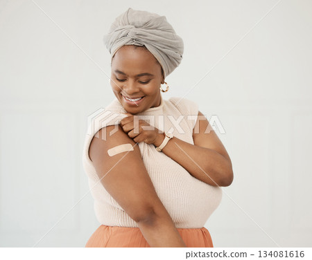 Covid, smile and black woman with plaster on arm in studio for injection on medical insurance. Happy African female on a white background with vaccine, safety compliance and medicine mockup space 134081616