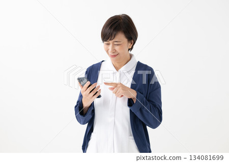 A woman in a white coat with a smartphone 134081699