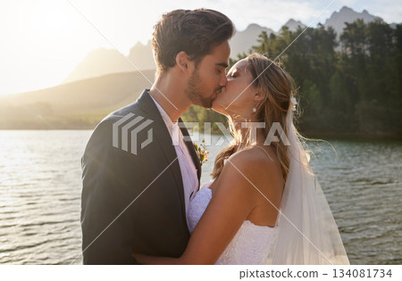 Love, wedding and a newlywed couple kissing by a lake outdoor in celebration of their marriage for romance. Water, summer or kiss with a bride and groom bonding together in tradition after ceremony Love, wedding and a newlywed couple kissing by a lake outdoor in celebration of their marriage for romance. Water, summer or kiss with a bride and groom bonding together in tradition after ceremony 134081734