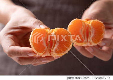 Mandarin orange fruit holding by hand and eating 134081783
