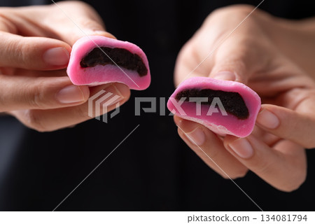 Daifuku mochi (Traditional Japanese sweet) stuffed with red bean paste holding by hand and eating 134081794