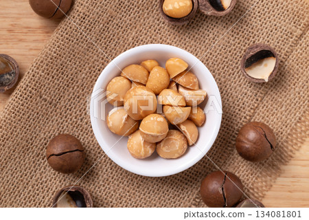 Peeled macadamia nuts in a bowl on brown background, Top view Peeled macadamia nuts in a bowl on brown background, Top view 134081801