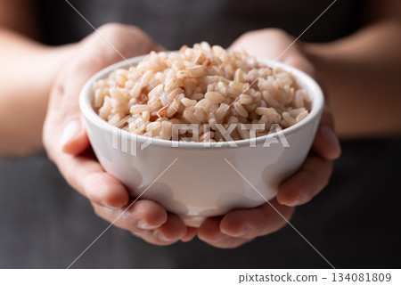 Cooked Thai brown rice in a bowl holding by hand, Healthy eating 134081809