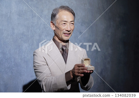 Senior man in a suit giving a ring Black background Senior man in a suit giving a ring Black background 134082039