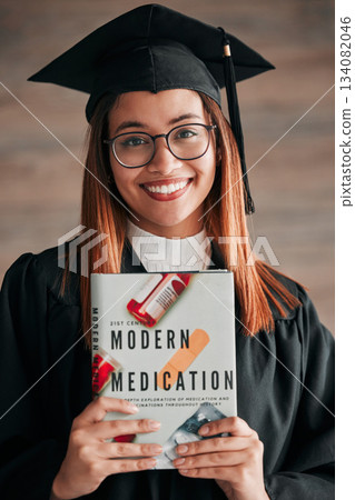 Doctor graduate, woman portrait and medical textbook of a young student happy from graduation. Learning book, happiness and excited female ready for university education with a smile from knowledge 134082046