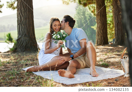 Couple kiss, love and flowers on picnic, summer with freedom and adventure, affection in relationship and care outdoor. Happy people together in nature, commitment and trust with romance in forest 134082135