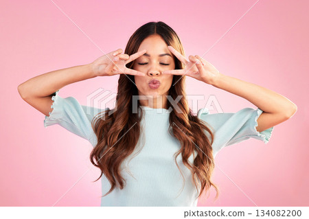 Peace sign, kiss and face of woman in studio for happiness, satisfaction and positive gesture. Silly, goofy and gen z with female isolated on pink background for confidence, pride and emoji symbol Peace sign, kiss and face of woman in studio for happiness, satisfaction and positive gesture. Silly, goofy and gen z with female isolated on pink background for confidence, pride and emoji symbol 134082200