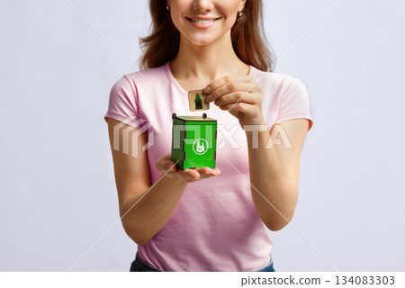 Conceptual Image For Waste Sorting. Woman Putting Card With Drinking Glass Icon Into Small Wooden Toy Garbage Container, Unrecognizable Lady Standing Over Light Background In Studio, Free Space Conceptual Image For Waste Sorting. Woman Putting Card With Drinking Glass Icon Into Small Wooden Toy Garbage Container, Unrecognizable Lady Standing Over Light Background In Studio, Free Space 134083303