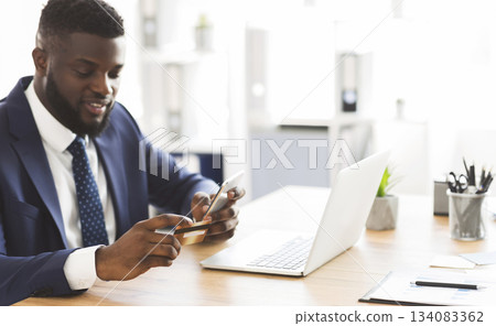 Online banking. African american general manager making online payment on phone at office, holding credit card, free space 134083362