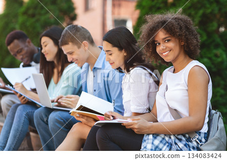 Studying Together. Cheerful African American Student Girl Preparring For Exams Outdoors With Her University Friends, Selective Focus 134083424