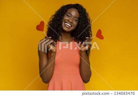 Be my valentine. Sweet smiling african girl with red hearts over yellow background 134083470