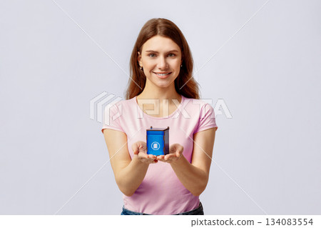 Waste Separation Concept. Portrait Of Smiling Young Lady Holding Little Blue Toy Recycle Bin For Paper Garbage, Millennial Woman Promoting Trash Recycling, Standing On Light Grey Background Waste Separation Concept. Portrait Of Smiling Young Lady Holding Little Blue Toy Recycle Bin For Paper Garbage, Millennial Woman Promoting Trash Recycling, Standing On Light Grey Background 134083554