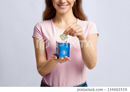 Garbage Sorting Conceptual Image With Woman Putting Card With Paper Waste Icon Into Small Wooden Toy Trash Container, Unrecognizable Lady Standing Over Light Background In Studio, Copy Space 134083559
