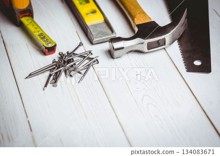 Flat design is showing tape measure, nails, spirit level, hammer, saw blade on white painted plank 134083671