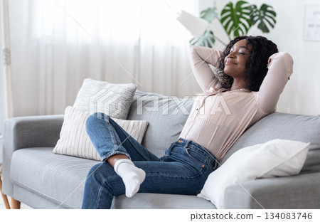 Weekend At Home. Relaxed Black Woman Leaning Back On Couch With Closed Eyes, Resting On Comfortable Sofa In Cozy Living Room With Hands Behind Head, Enjoying Spending Day Off, Copy Space 134083746