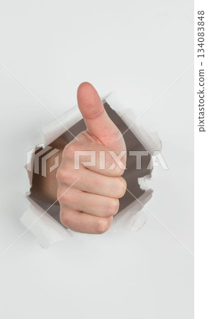 Thumbs up ripping through paper 134083848