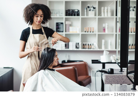Young woman enjoying haircut at beauty salon with black master, free space 134083879