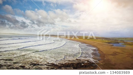 Flat illustration is showing foamy ocean waves rolling onto sandy shoreline near rocky headland Flat illustration is showing foamy ocean waves rolling onto sandy shoreline near rocky headland 134083989