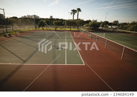 Empty tennis court is being shown in flat design featuring net posts, white lines, chainlink fence Empty tennis court is being shown in flat design featuring net posts, white lines, chainlink fence 134084149