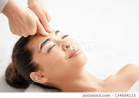 Attractive young korean woman receiving acupressure head massage in spa salon,calm asian lady lying on table with closed eyes, enjoying professional beauty treatments and wellness procedures, closeup Attractive young korean woman receiving acupressure head massage in spa salon,calm asian lady lying on table with closed eyes, enjoying professional beauty treatments and wellness procedures, closeup 134084213