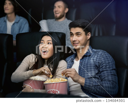 Happy young couple with popcorn watching movie in cinema 134084301