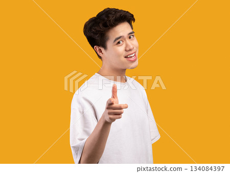 I Pick You. Portrait of casual asian guy in white t-shirt pointing finger at camera, posing isolated over orange studio background wall. Positive smiling man choosing and indicating 134084397