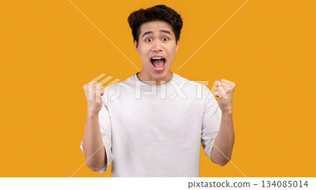 Yes, Great News. Portrait of excited asian guy screaming and shaking clenched fists raised up in the air, isolated over orange studio background. Joyful man cheering and shouting, celebrating triumph Yes, Great News. Portrait of excited asian guy screaming and shaking clenched fists raised up in the air, isolated over orange studio background. Joyful man cheering and shouting, celebrating triumph 134085014