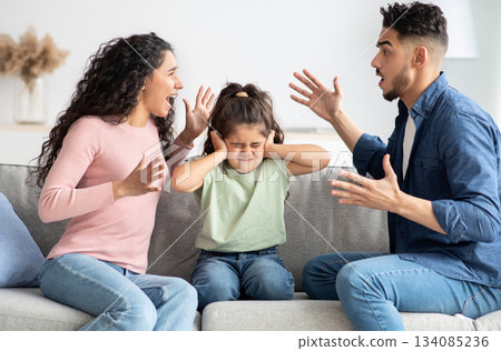 Parental Quarrels. Arab Man And Woman Arguing In Front Of Their Child, Upset Little Girl Covering Ears With Hands Not To Listen Conflict, Stressed Female Kid Sitting Between Shouting Parents Parental Quarrels. Arab Man And Woman Arguing In Front Of Their Child, Upset Little Girl Covering Ears With Hands Not To Listen Conflict, Stressed Female Kid Sitting Between Shouting Parents 134085236