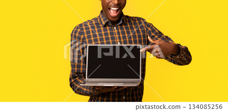 Check This Website. Joyful African Guy Pointing At Laptop Computer With Black Blank Screen, Standing Isolated Over Yellow Background, Demonstrating Free Place For Your Design, Mockup With Copy Space Check This Website. Joyful African Guy Pointing At Laptop Computer With Black Blank Screen, Standing Isolated Over Yellow Background, Demonstrating Free Place For Your Design, Mockup With Copy Space 134085256