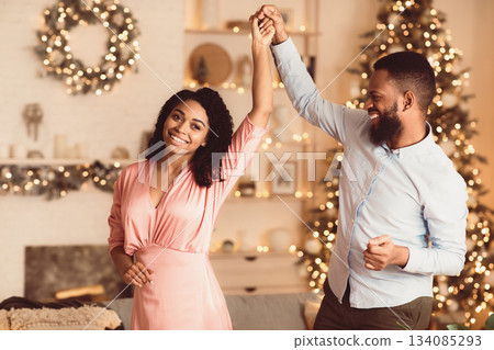 Love And Affection. Portrait of smiling millennial african american man and woman dancing. Happy black couple enjoying spending time together at a party at home, celebrating event Love And Affection. Portrait of smiling millennial african american man and woman dancing. Happy black couple enjoying spending time together at a party at home, celebrating event 134085293