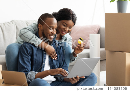 Online Shopping Concept. Cheerful Black Spouses With Laptop Choosing Furniture After Moving To New Home, Happy African American Couple With Computer And Credit Card Purchasing In Internet, Closeup Online Shopping Concept. Cheerful Black Spouses With Laptop Choosing Furniture After Moving To New Home, Happy African American Couple With Computer And Credit Card Purchasing In Internet, Closeup 134085306