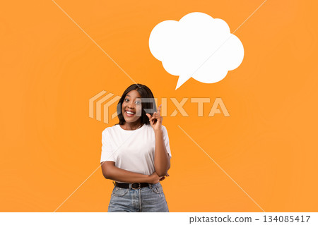 Inspired african american young lady holding empty communication bubble and pointing finger up, orange studio background. Black lady in casual with blank clipart, sharing creative ideas, panorama Inspired african american young lady holding empty communication bubble and pointing finger up, orange studio background. Black lady in casual with blank clipart, sharing creative ideas, panorama 134085417