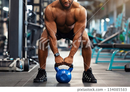 Muscular shirtless african american guy bodybuilder exercising with kettlebell at gym, looking at camera, copy space. Athletic black man making weightlifting or powerlifting, working on body musculs Muscular shirtless african american guy bodybuilder exercising with kettlebell at gym, looking at camera, copy space. Athletic black man making weightlifting or powerlifting, working on body musculs 134085583