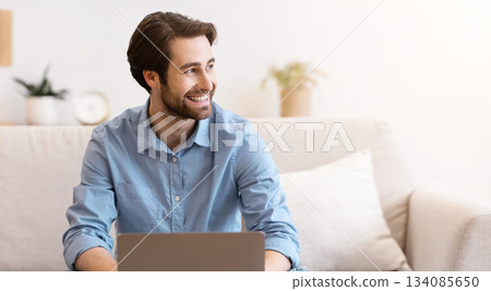 Cheerful Businessman Works On Laptop Online Smiling Looking Aside Sitting On Sofa At Home. Happy Freelancer Man Working On Computer Distantly Indoors. Freelance Job Concept Cheerful Businessman Works On Laptop Online Smiling Looking Aside Sitting On Sofa At Home. Happy Freelancer Man Working On Computer Distantly Indoors. Freelance Job Concept 134085650