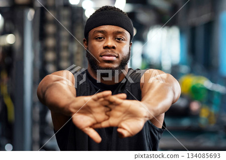 Warming up concept. Portrait of african american bearded sportsman stretching his hands before workout, muscular young black man bodybuilder training at gym, closeup, copy space Warming up concept. Portrait of african american bearded sportsman stretching his hands before workout, muscular young black man bodybuilder training at gym, closeup, copy space 134085693