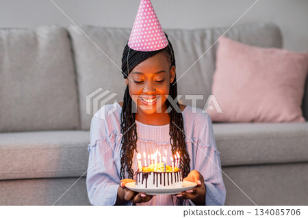 Smiling african american woman in party hat showing her online friend cake, celebrating birthday online during self-isolation, happy black lady having video conference with family or boyfriend Smiling african american woman in party hat showing her online friend cake, celebrating birthday online during self-isolation, happy black lady having video conference with family or boyfriend 134085706