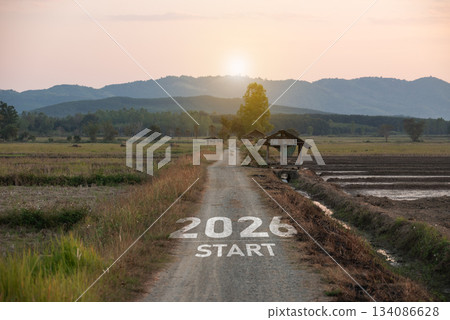 New Year 2026. Scenic rural landscape featuring a dirt path marked with 2026 start, surrounded by fields, trees, and mountains at sunrise, ideal for vision and future themes. New Year 2026. Scenic rural landscape featuring a dirt path marked with 2026 start, surrounded by fields, trees, and mountains at sunrise, ideal for vision and future themes. 134086628