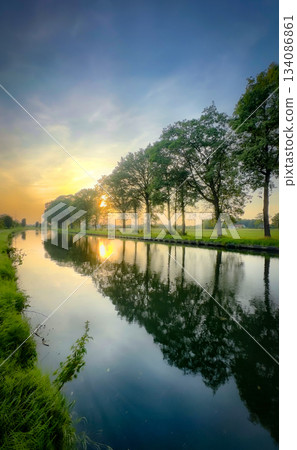 Experience serene sunset reflections dancing on a tranquil river, creating a peaceful landscape 134086861